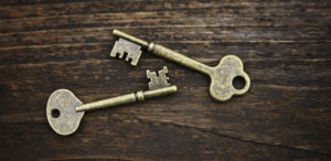 two gold keys on wood background