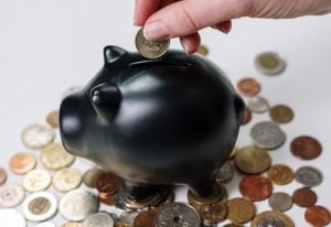 coins being put into black piggy bank