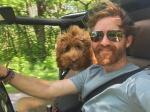 man and his dog riding in a jeep